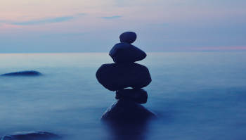 image of a lake with a column of pebbles in the twilight