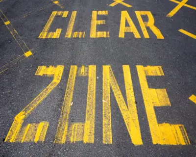 Comfort zone of coaching: a paved road with 'Clear Zone' painted over it in yellow